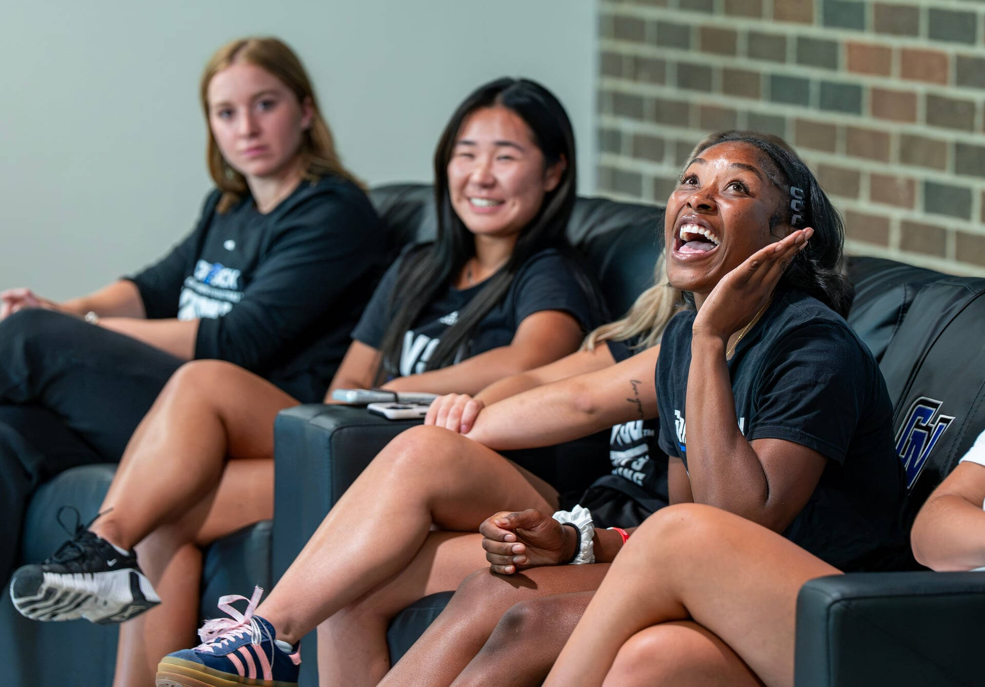 student athletes in black t-shirts sit in black chairs during a panel discussion